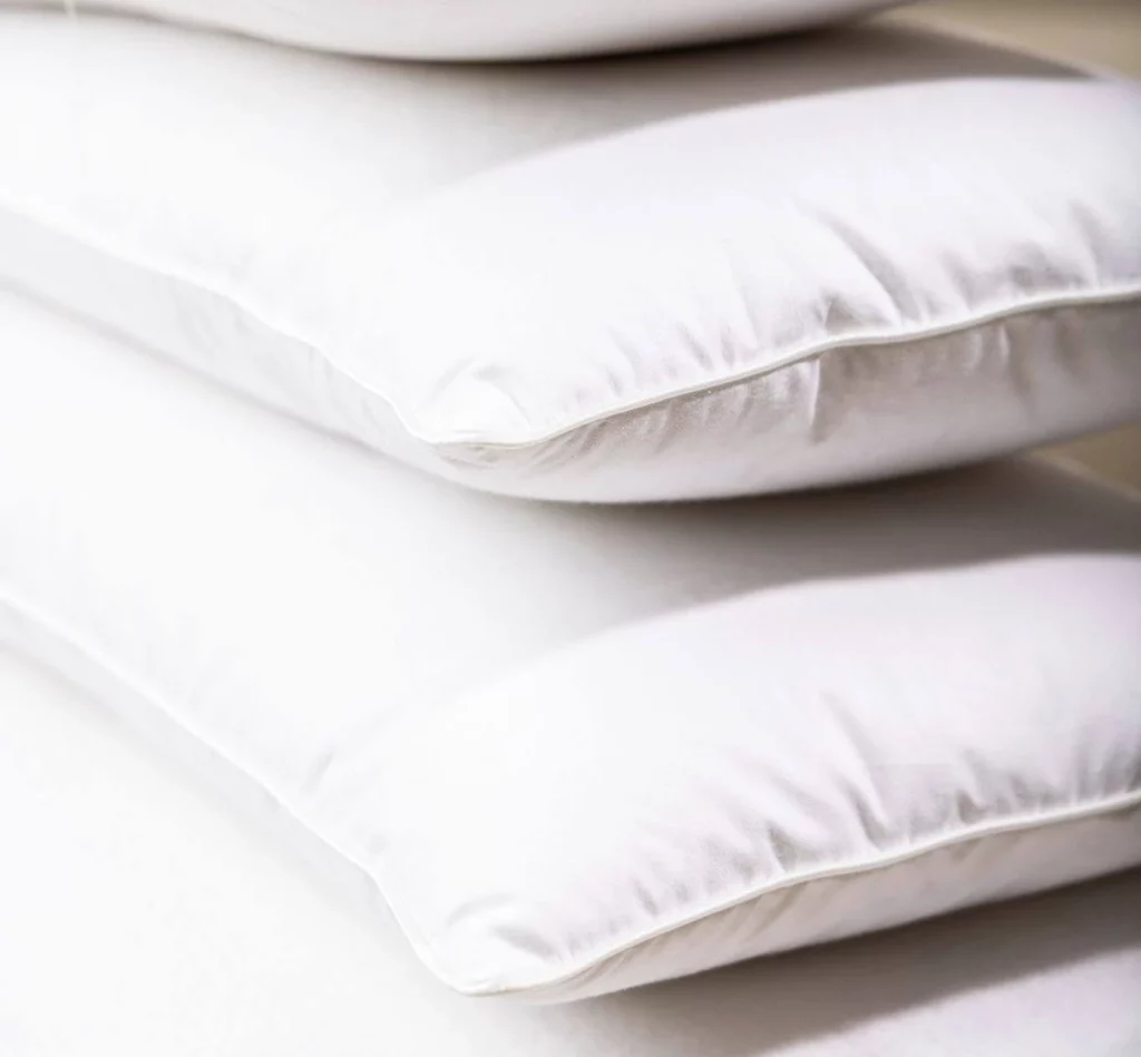 Four luxury white pillows stacked on top of each other.