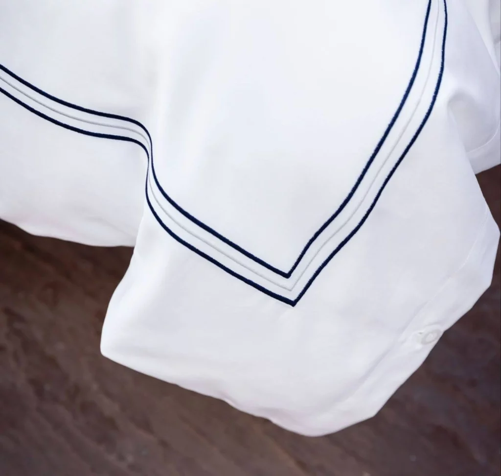 Luxury white bed linen with blue lines created for marine conditions.